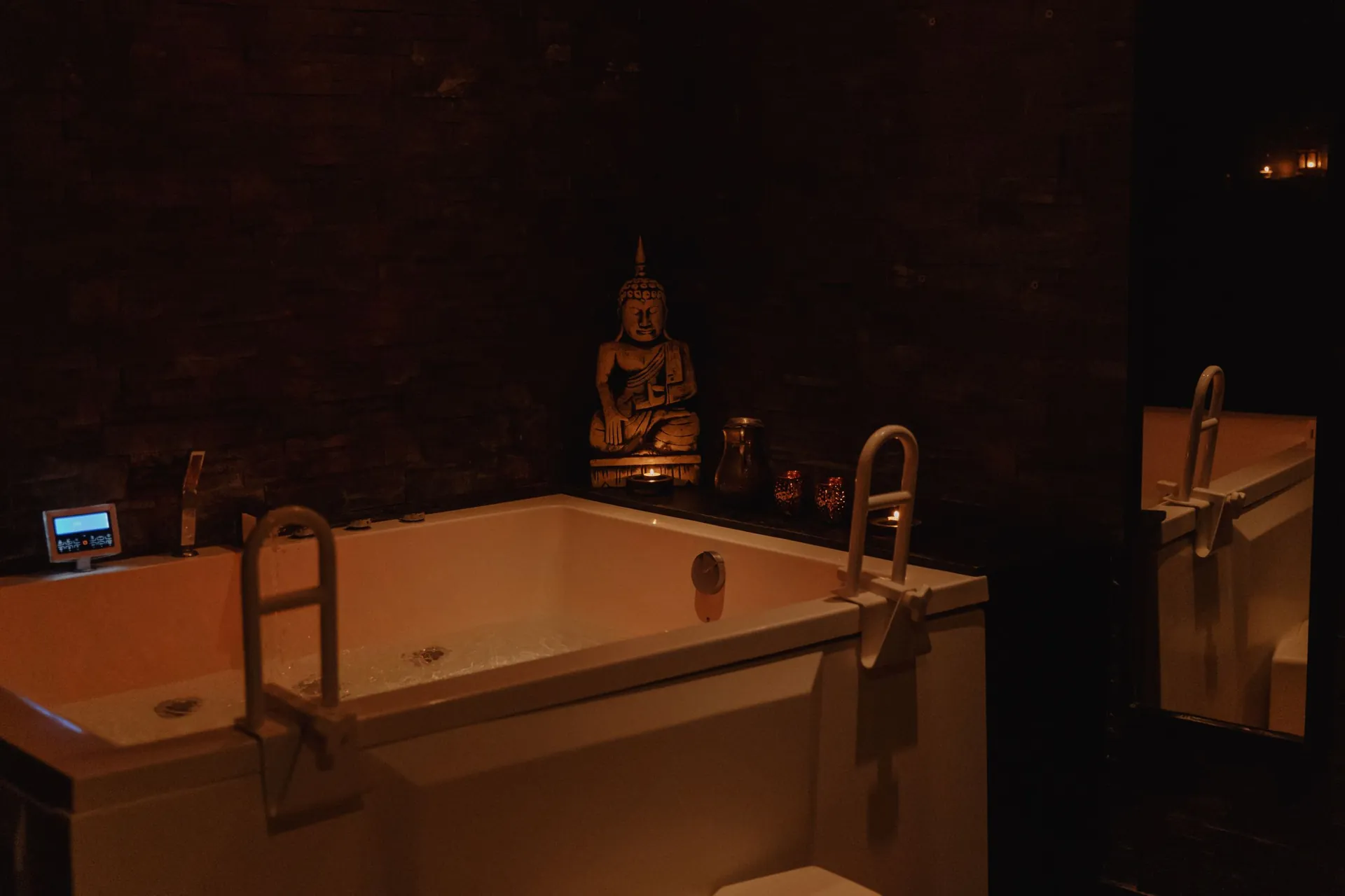 Le jacuzzi privatif de Sensation Spa, éclairé à la bougie, veillé par une statue de Bouddha.