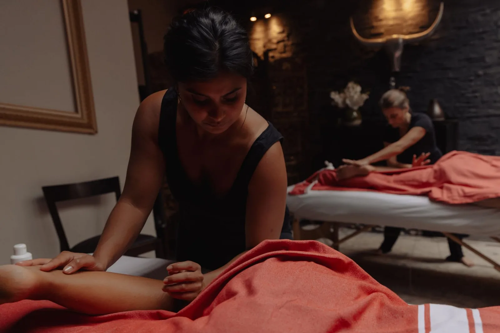 Two massage tables side by side, coral linen and soft lighting, in the double room at Sensation Spa Paris