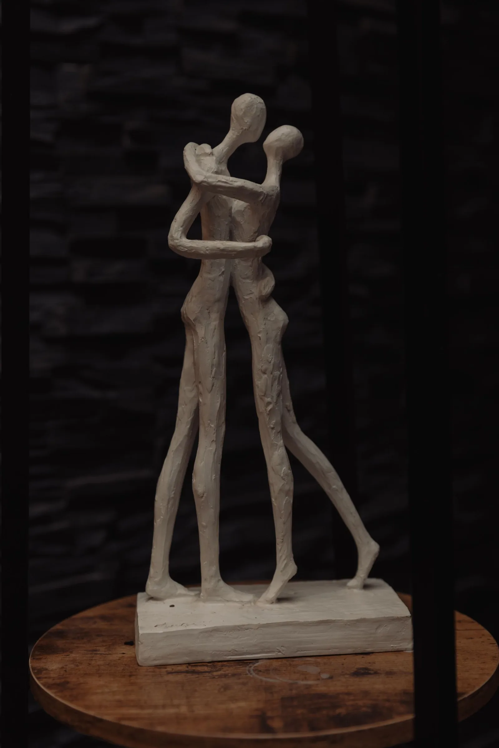 White sculpture of an embracing couple on a wooden side table at the spa