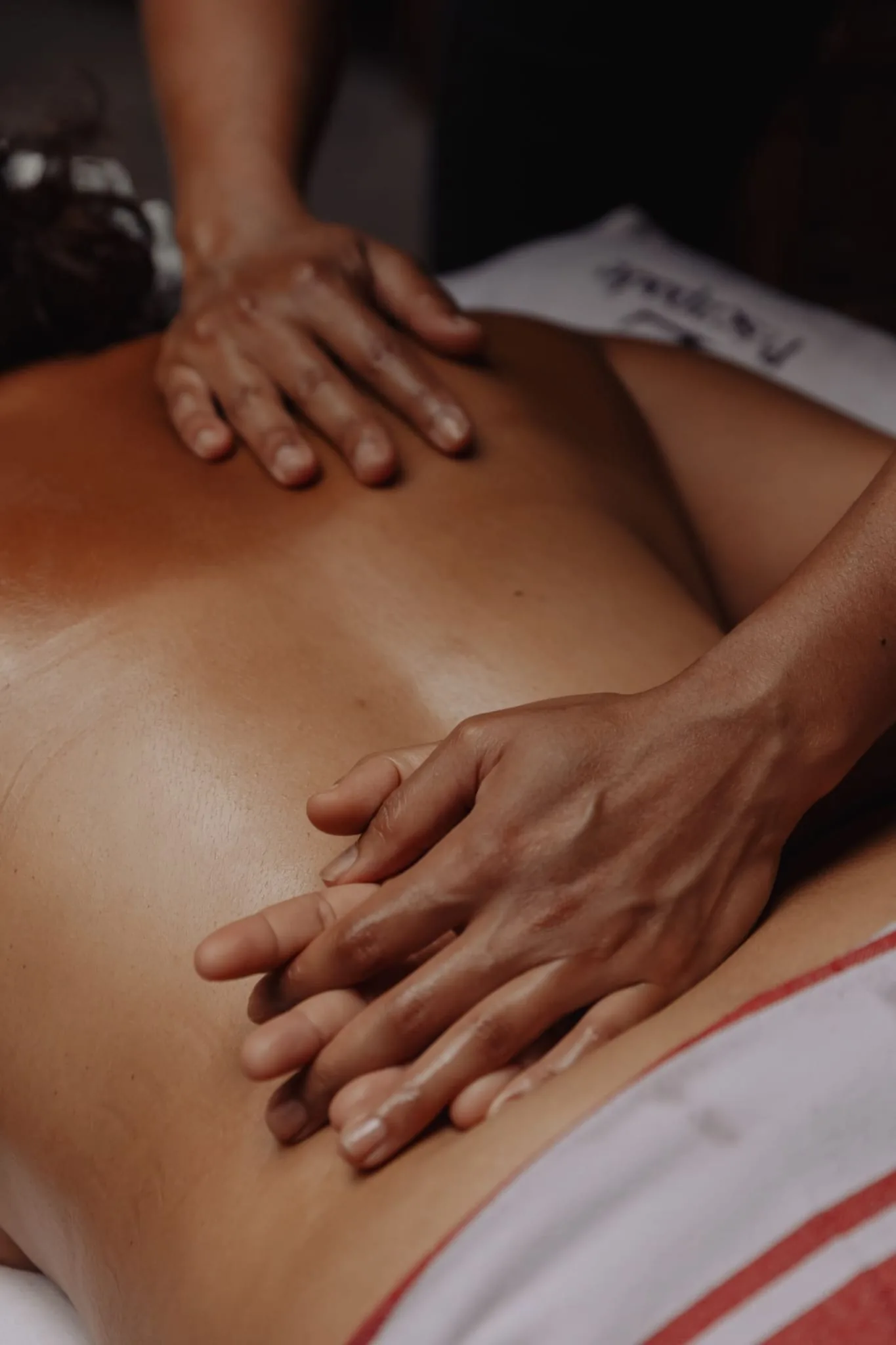 Mains d'un praticien travaillant le dos d'une cliente, en gros plan, dans une cabine de Sensation Spa Paris.
