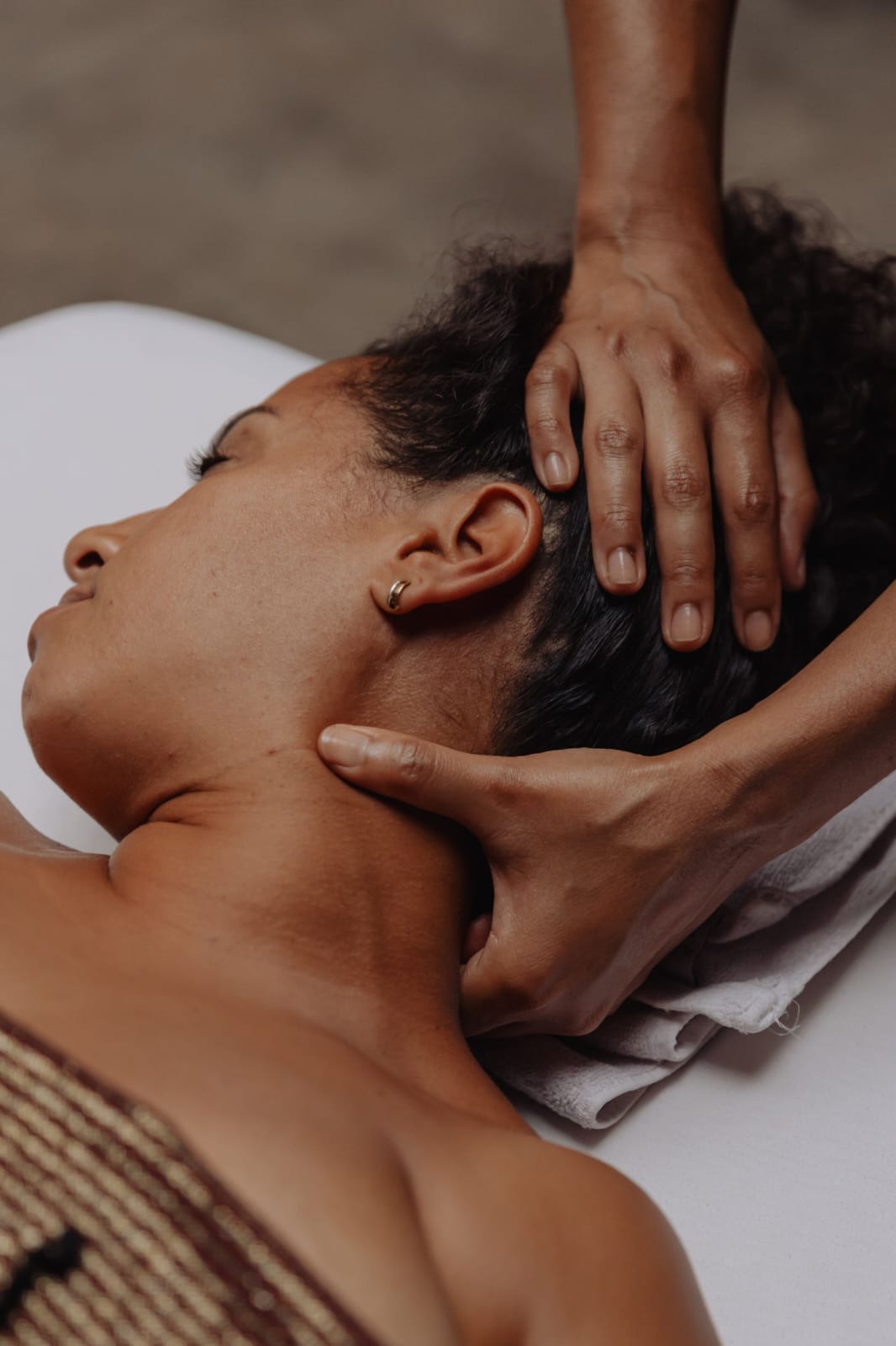 Massage du crâne et de la nuque, mains de la praticienne sous la tête.